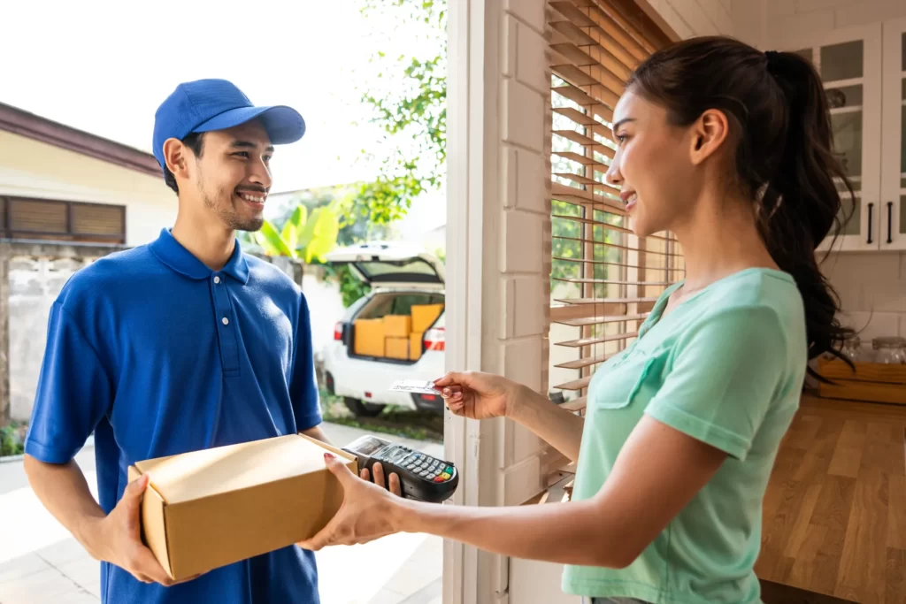 friendly delivery man passing package to woman at utc